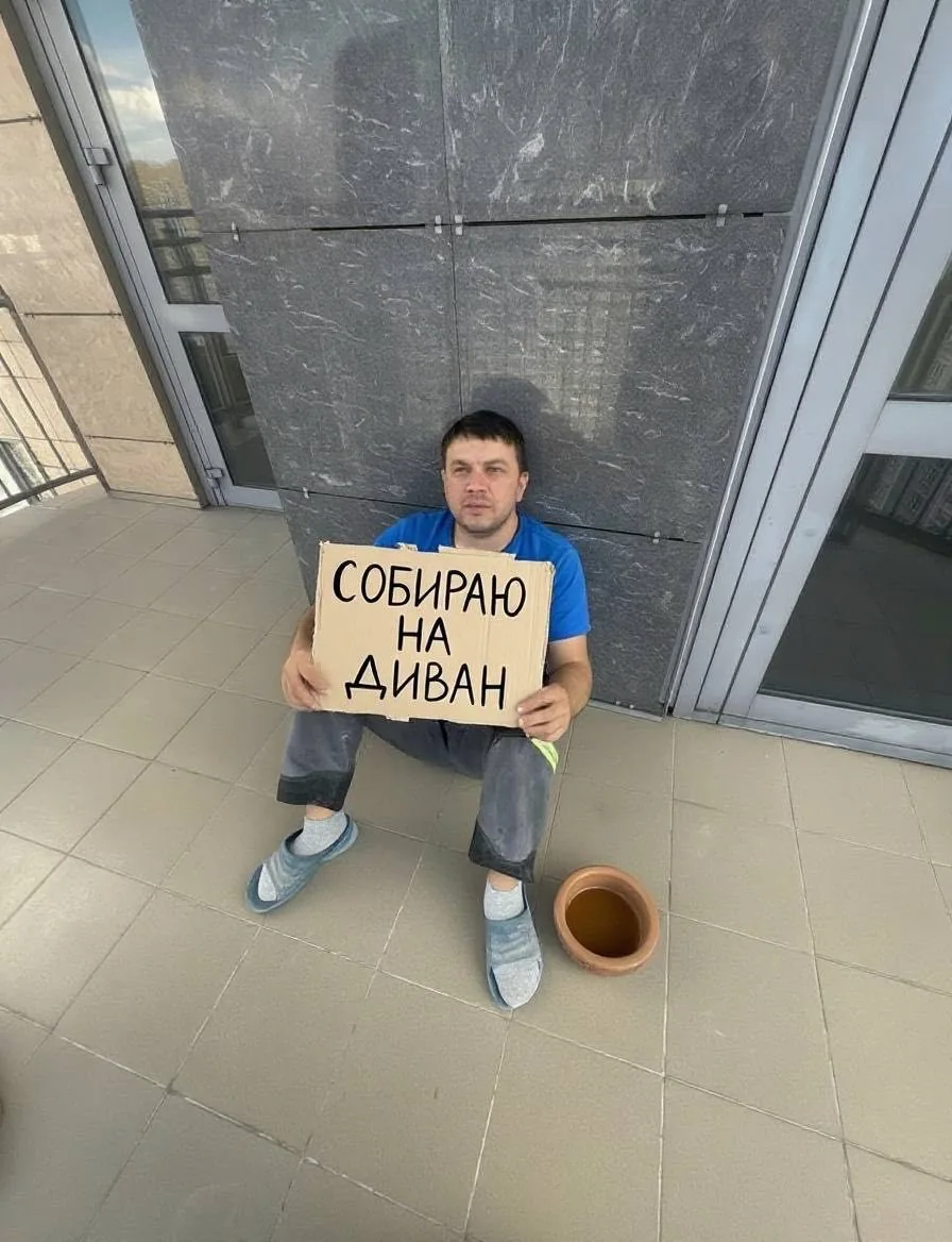 Рабочий сидит с картонной табличкой «Собираю на диван»